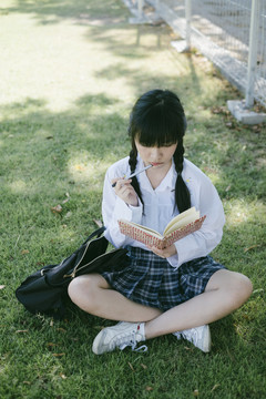 留着辫子和流苏头发的女学生坐在地上看书。