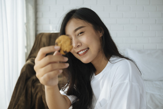 可爱的亚洲女人拿着一块饼干微笑着。