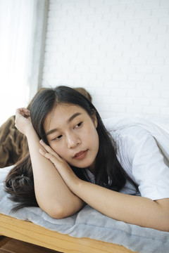 在卧室里，可爱的亚洲女人把头靠在胳膊上，快乐的女孩，熟睡的概念。