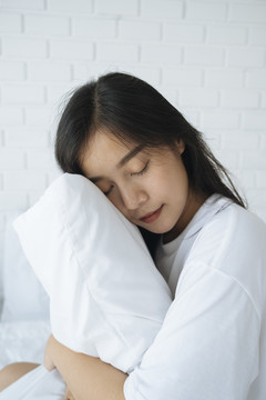可爱的亚洲年轻女士抱着白色枕头睡觉-睡得好的概念。