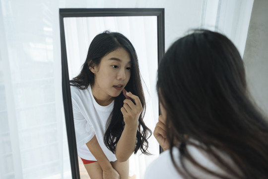 性感的泰国亚洲女人在镜子前涂上唇膏，带着性感的姿势。
