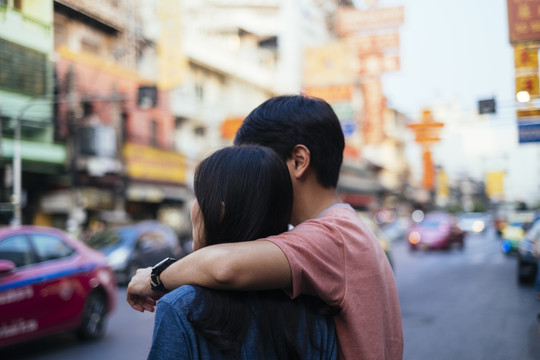 侧视图-亚泰夫妇一起在城市旅行。互相拥抱。