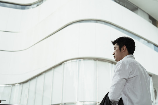 穿着白色正式衬衫的成熟亚洲商人看着曼谷市的白色建筑。