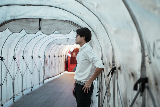 穿白衬衫的黑发男人站在临时隧道里等他的朋友。