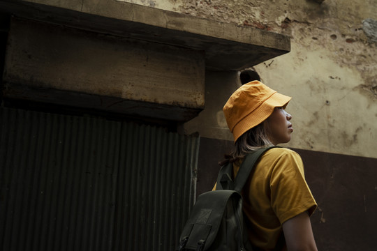 一个穿着黄色t恤的背包女孩在老城区散步。