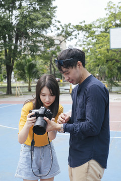 男摄影师和女模特一起用数码相机看照片。