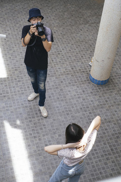 男摄影师在大楼里为十几岁的模特女孩拍照。