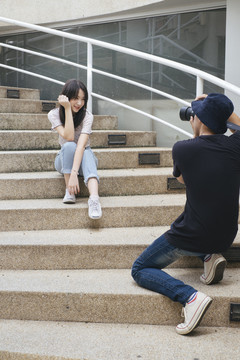 男摄影师坐在鹅卵石楼梯上给模特儿拍照。