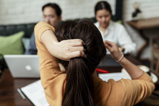 后视图-在商务会议上系着凌乱头发的女人。