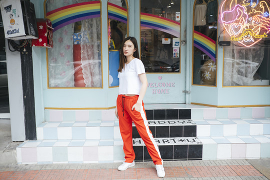 时尚写真-身穿白色衬衫和红色运动裤的泰国亚裔年轻女子站在街上。