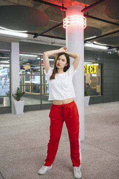 全长时尚肖像-美丽的亚洲年轻女子在白色衬衫和红色运动裤红色霓虹灯在头上。