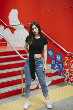 时尚写真-身穿黑色衬衫和牛仔裤裤子的泰国亚裔年轻女子在红色楼梯上涂鸦。