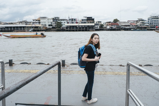 一位背包客妇女在Chao Praya河等船。