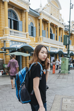 穿黑衬衫的背包女在曼谷用智能手机旅行。