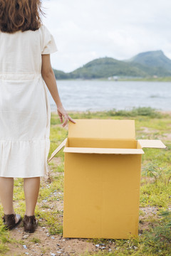 作物图片-年轻的亚泰妇女时髦卷发白色连衣裙站在湖边纸板箱。