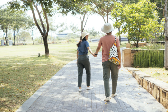 一对戴着同一顶帽子的亚泰夫妇在公园散步。旅行者夫妇在公园里旅行。