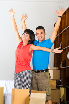 房地产市场-年轻的印尼夫妇搬家或公寓，他们打开搬家箱