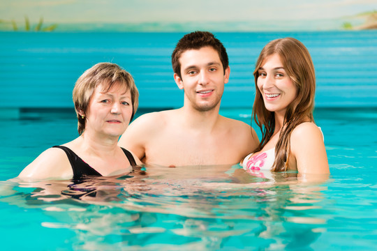 健康-成熟的女人和年轻的夫妇在游泳池游泳或做水上体操，也是一个概念的青年井