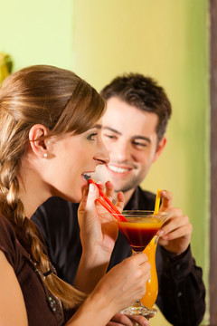 在酒吧或餐馆里喝鸡尾酒的幸福的年轻夫妇