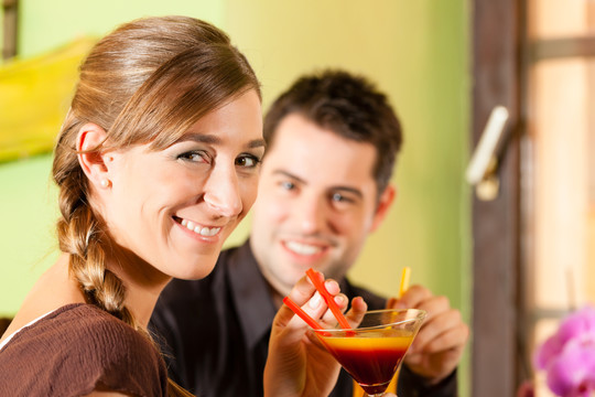 在酒吧或餐馆里喝鸡尾酒的幸福的年轻夫妇