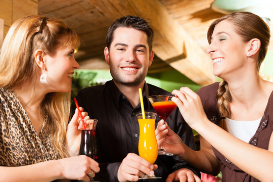 快乐的年轻人在酒吧或餐馆喝鸡尾酒