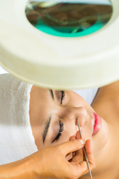 亚洲女人躺在美容spa里用粉刺压缩机治疗