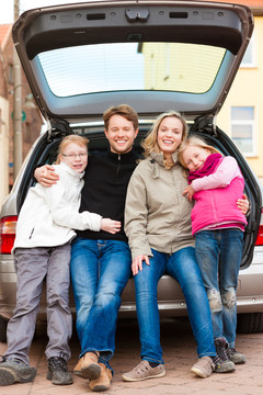 一家人，母亲，父亲和孩子，坐在后备箱里，他们旅行