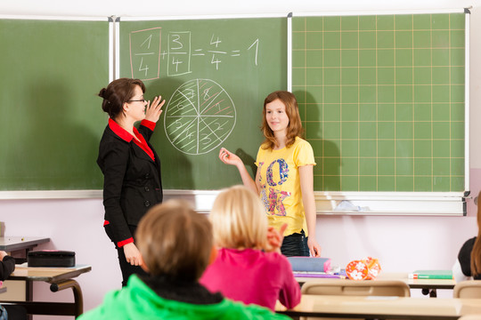 教育-年轻的女教师和学生在他的形式的小学或小学教学