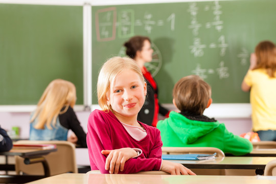 教育-年轻的女教师和学生在他的形式的小学或小学教学