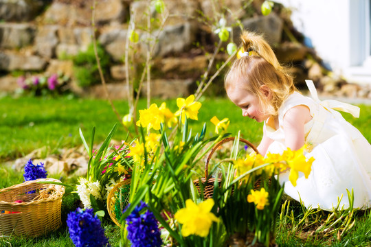春天，小女孩在草地上寻找复活节彩蛋，她发现了一个复活节彩蛋