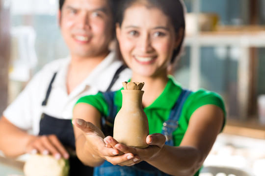 两个亚洲人或印尼人拿着烤粘土和一个手工制作的花瓶