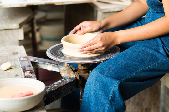 女陶工在陶工的轮子上制作碗