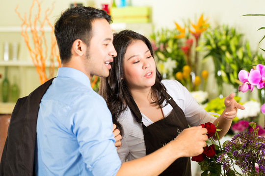 友好的亚洲花商或花店的女售货员给顾客提供建议