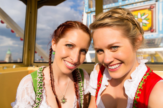 穿着传统巴伐利亚服装的年轻女性——迪恩德尔或特雷希特——在节日或啤酒节上骑着摩天轮