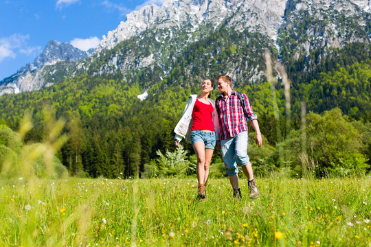 幸福夫妻走在山前的草地上全景
