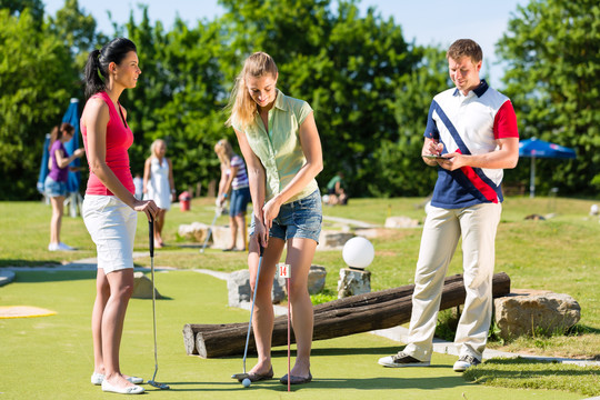 人们，男人和女人，在美丽的夏日打迷你高尔夫