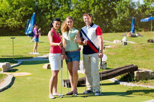 人们，男人和女人，在美丽的夏日打迷你高尔夫