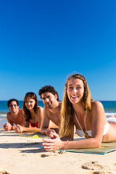 四个朋友组成的小组-男人和女人-在海滩上享受假期的乐趣