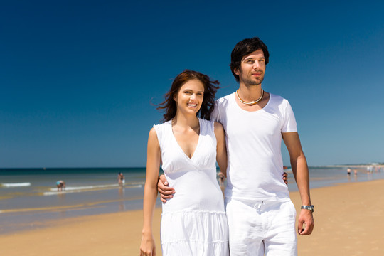 一对嬉戏的情侣在海边度过暑假，他们手挽手散步