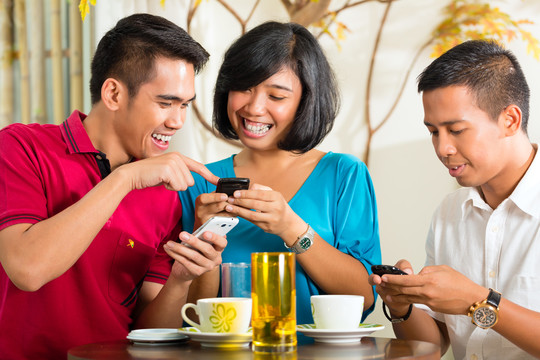 亚洲人一起玩手机，喝咖啡或鸡尾酒
