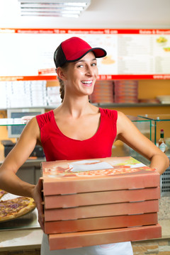 拿着几个比萨饼盒微笑着的女人