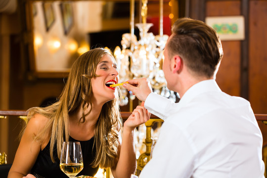 一对男女在一家高级餐厅吃快餐和薯条，背景是一盏大吊灯