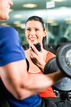 男子或健美运动员与私人健身教练在健身房练习哑铃运动，特写