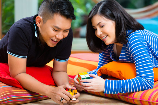 年轻的印尼夫妇-男人和女人-在家玩魔方