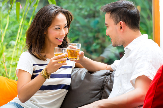 年轻的印尼夫妇-男人和女人-在家里，一起喝酒，碰杯