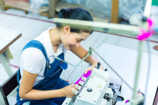 亚洲女裁缝或印尼工厂的工人用工业缝纫机缝纫，她非常准确