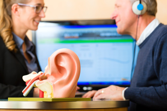 有听力问题的老年人或退休人员进行听力测试，可能需要助听器，前景是人耳模型