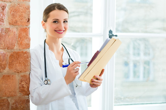年轻的女医生站在诊所的橱窗边写着文件或卷宗
