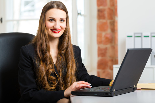 年轻的女商人或秘书在办公室工作，在笔记本电脑上写字