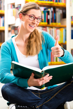 学生-年轻女子或女孩坐在图书馆看书学习